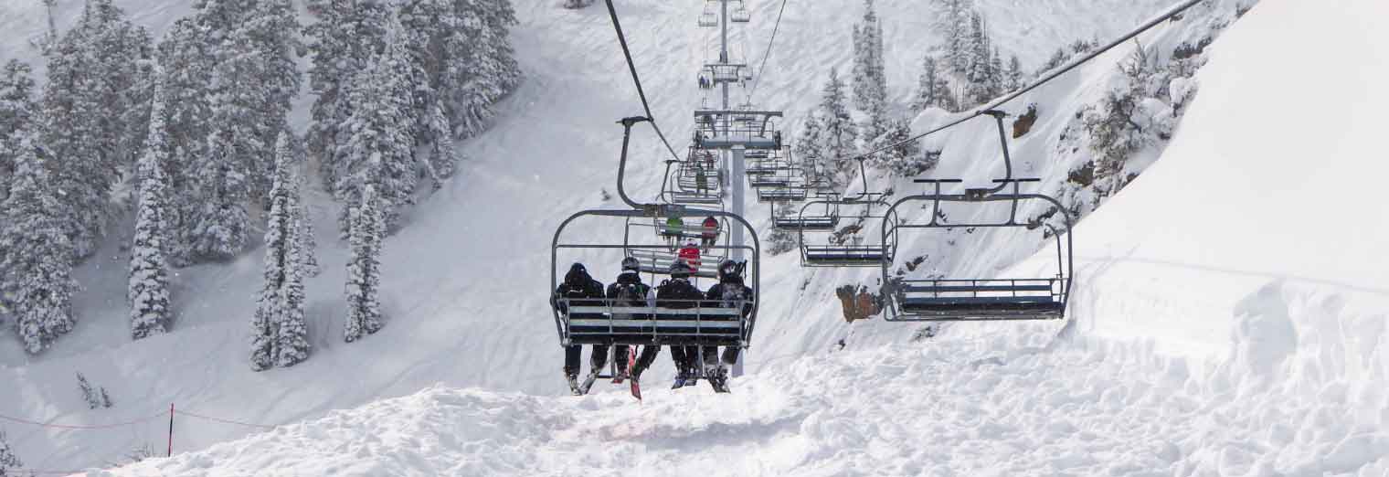 A group of people on a ski lift enjoys stunning mountain views, making the most of Autumn Vacation Values.