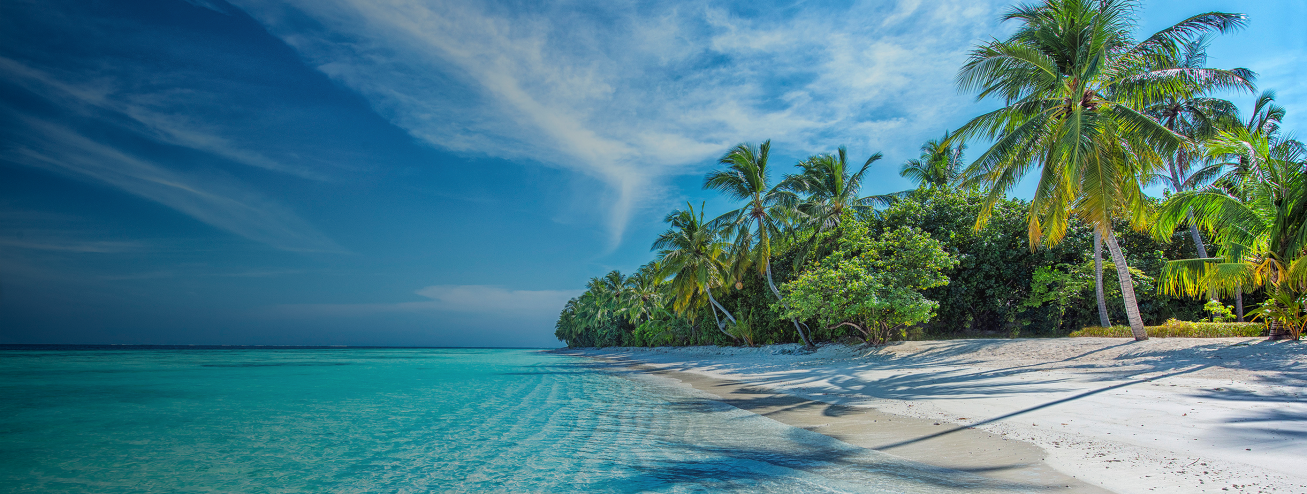 A tropical beach with clear turquoise water, white sand, and lush green palm trees under a bright blue sky with scattered clouds—like the relaxing getaway you dream about while waiting at Joe’s Airport Parking.
