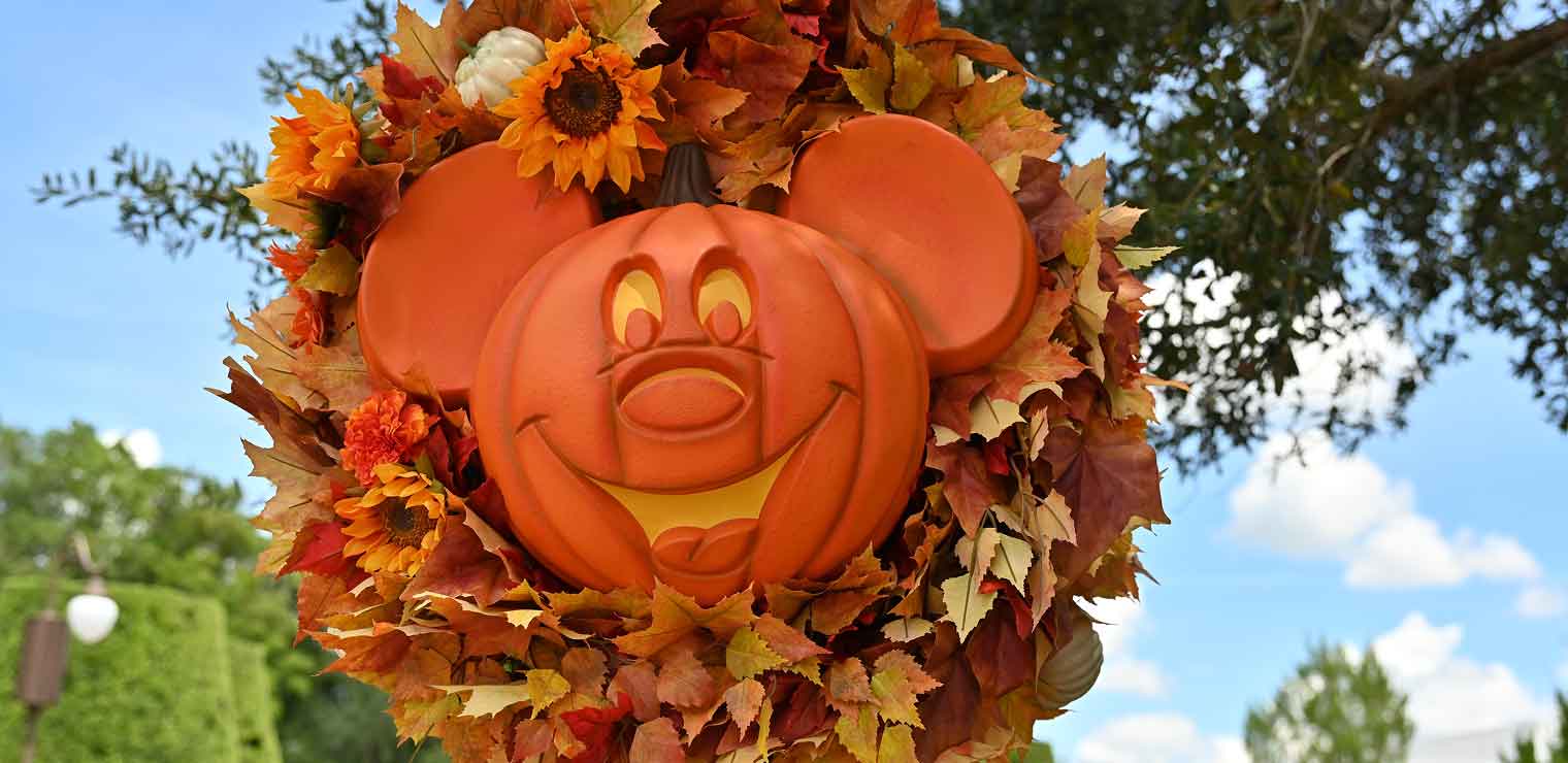 A Mickey Mouse-shaped pumpkin decoration, reminiscent of Joe’s Airport Parking seasonal displays, surrounded by a wreath of fall-colored autumn leaves and sunflowers.
